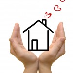 Hands protecting drawn house, hearts coming out of chimney
